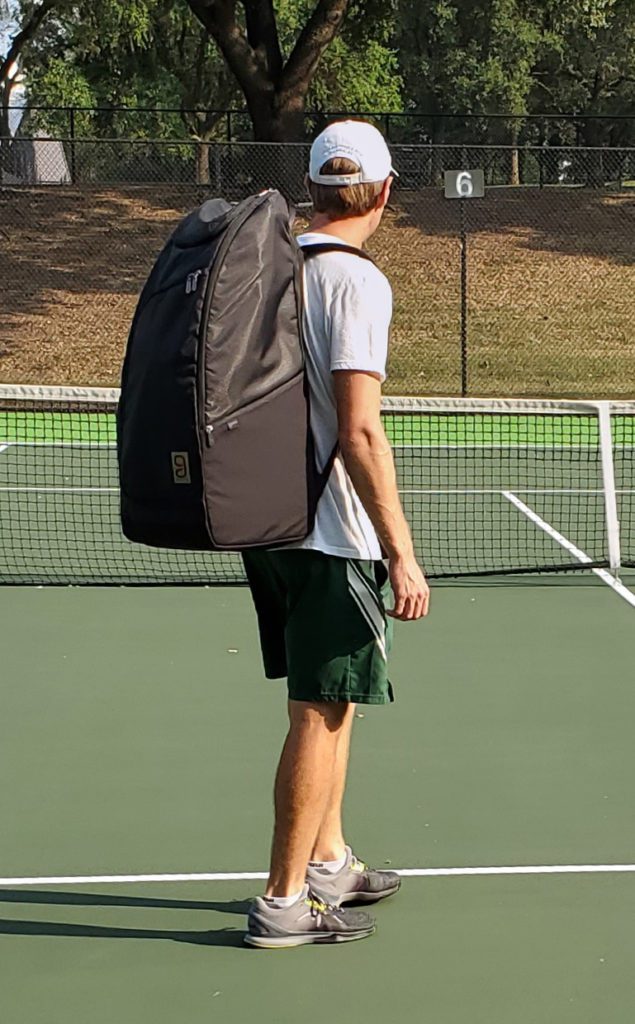 Man wearing the Geau tennis bag on a tennis court