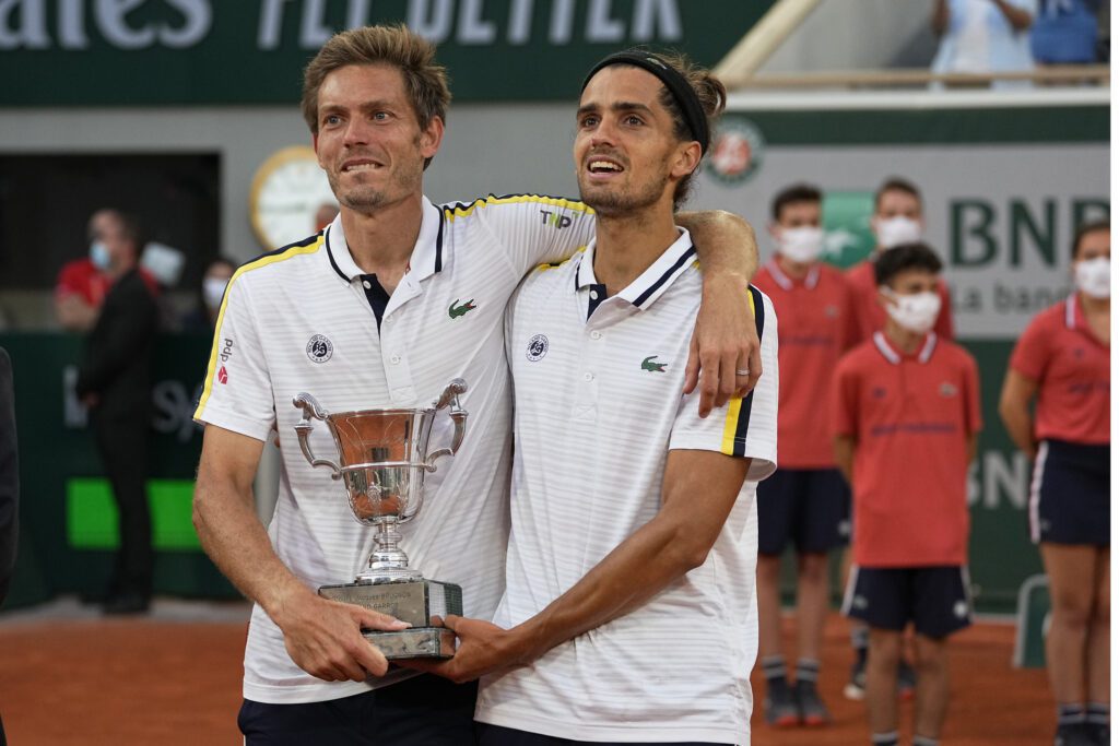 Nicolas Mahut and Pierre Hugues-Herbert embrace after their Roland Garros title in 2021. 