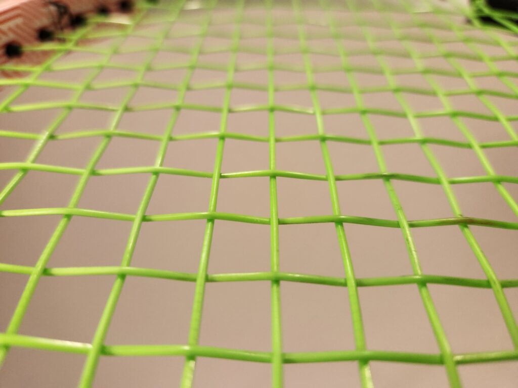 Polyester tennis strings on a tennis racquet